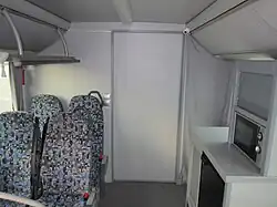 Салон, вид назад. Видны мини-кухня и вход в туалет. Справа за шторкой — проход к спальному месту водителя