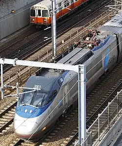 Высокоскоростной поезд «Acela Express» обгоняет вагонов оранжевой линии