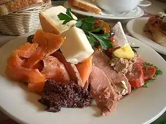 Вариант антипасто: кусочки копчёных лосося, курятины и свинины, колбасы сорта «кабана», козьего сыра твёрдых сортов и сыра сорта бри, паштет, тапенада, оливки, песто «руккола», индийский томатный соус чатни