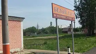 Знак на платформе, на фоне жилой посёлок на севере