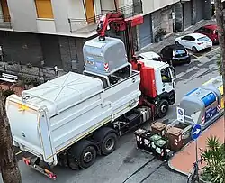 Грузовик собирает мусор из отведённых мусорных баков