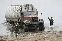 Речное звено в сложенном виде (состоит из двух средних и двух крайних понтонов, соединенных шарнирными соединениями) из комплекта ПМП на базовом шасси КрАЗ-255Б.