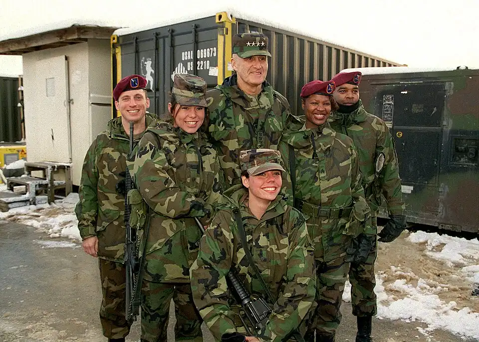 Генерал Генри Х. Шелтон, председатель Объединенного комитета начальников штабов, позирует для фотографий с солдатами на базе Команчи, Босния и Герцеговина, 22 декабря 1998 года. Шелтон посещает войска, развернутые в Боснии и Герцеговине для поддержки операции «Джойнт Фордж».