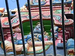 Образ Вишну проглядывает сквозь решетку позолоченной башни храма