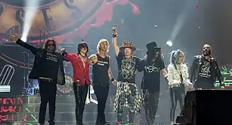 Guns N’ Roses на сцене Олимпийского стадиона в Лондоне 16 июня 2017 года. Слева направо: Диззи Рид, Ричард Фортус, Дафф Маккаган, Эксл Роуз, Слэш, Мелисса Риз, Фрэнк Феррер[англ.]