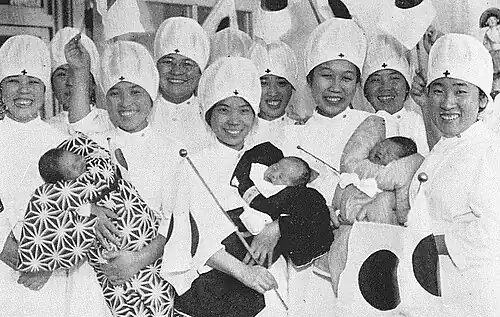 Медсёстры держат младенцев, родившихся в один день с принцем Акихито (23 декабря 1933 года). Фото из журнала «Исторические фотографии» (яп. 歴史写真 Рэкиси сясин), выпуск от февраля 1934 года. На новорождённом слева — кимоно с узором аса но ха