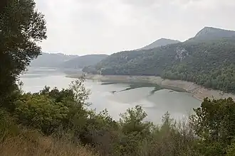 Вид на национальный парк Каратепе-Арсланташ, открывающийся из Каратепе. Заметна древняя крепостная стена в одноимённом музее под открытым небом[англ.] (слева) и водохранилище плотины Асланташ[англ.] (справа).