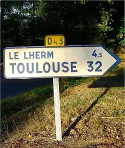 Дорожный знак, на котором указано старое название коммуны Le Lherm
