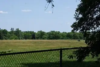 Вид на огороженную территорию в 2012 году. В 1970-х на этом месте стояли жилые дома и начальная школа