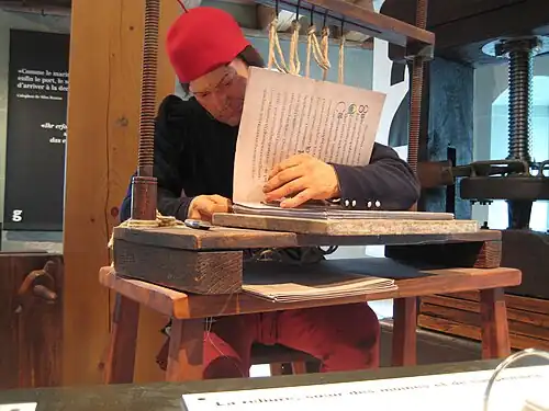 Восковая фигура переплетчика книги большого формата.