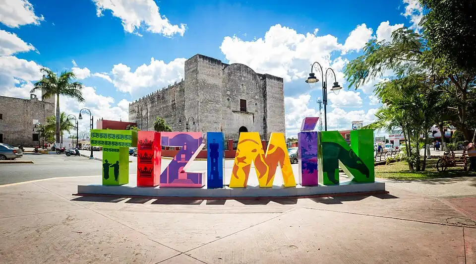 Стела с названием муниципалитета на фоне церкви всех святых