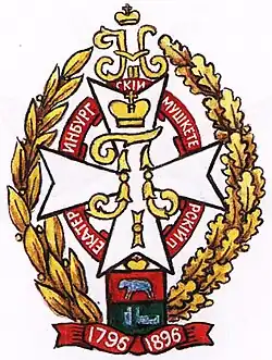 белый Мальтийский крест, на который положен золотой вензель (под короной) Императора Павла I. Под крестом сложенная венком эмалевая лента (красная или голубая) с надписью: «Екатеринбургский мушкетерский п.» Крест лежит на золотом венке из лавровых и дубовых листьев, в голове которого золотой вензель Императора Николая II. Под крестом герб Екатеринбурга под золотой короной (наверху, в красном поле, серебряный медведь, а внизу, на зеленом, серебряные печь и шахта). Под гербом лента с юбилейными датами: «1796-1896»