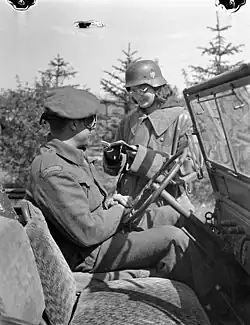 Полька в немецкой трофейной каске проверяет документы у канадского солдата при въезде в Харен, 7 мая 1945 года