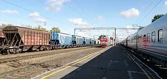 Два одноимённых пассажирских поезда противоположных направлений, Новороссийск-Москва (справа) и Москва-Новороссийск (в центре), встретились на станции Усмань. Слева — составы из вагонов для перевозки зерна (продукции сельскохозяйственной отрасли Липецкой области).