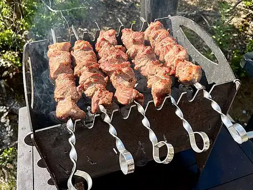 Свиной шашлык готовится на складном мангале